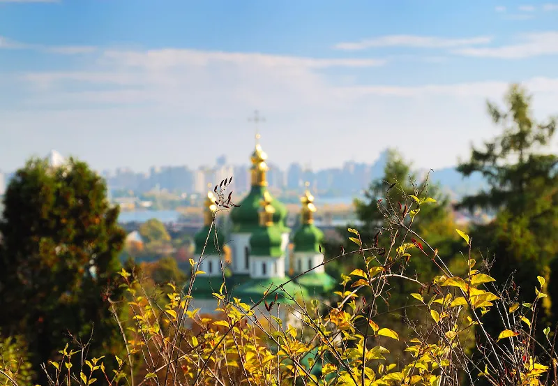 Zielone kopuły cerkwi nad Dnieprem na tle panoramy Kijowa jesienią
