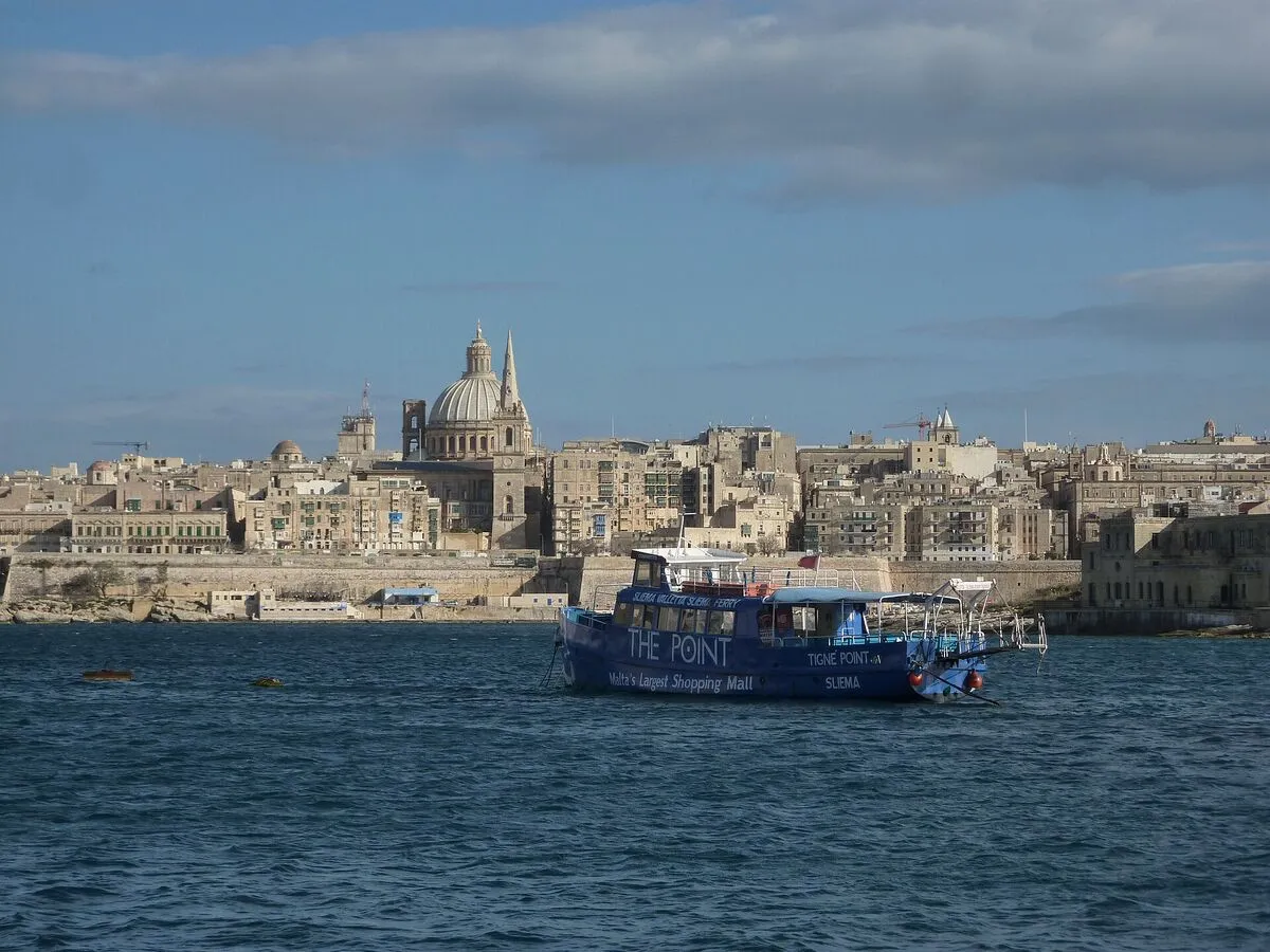 Valletta w wieczornym świetle, na wodzie zatoki łódź wycieczkowa