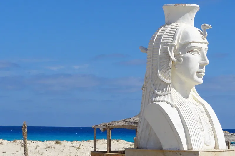 Biała rzeźba głowy faraona na plaży Kleopatry w Marsa Matruh, w tle turkusowe morze