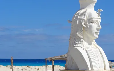 Biała rzeźba głowy faraona na plaży Kleopatry w Marsa Matruh, w tle turkusowe morze