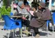 Dwaj starsi Tunezyjczycy, jeden w kapturze burnusa, rozmawiają przy stoliku kawiarni