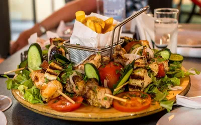 Półmisek meze w Limassol: grillowany kurczak i halloumi na szpadkach, warzywa i frytki
