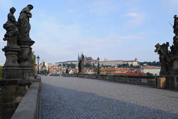 Pusty Most Karola o poranku z barokowymi figurami i widokiem na Hradczany