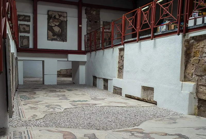 Wnętrze muzeum z fragmentami mozaikowej posadzki na żwirze i mozaikami na ścianach