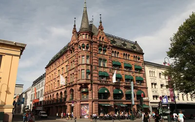 Neogotycka kamienica z wieżyczką i zielonymi markizami w centrum Oslo
