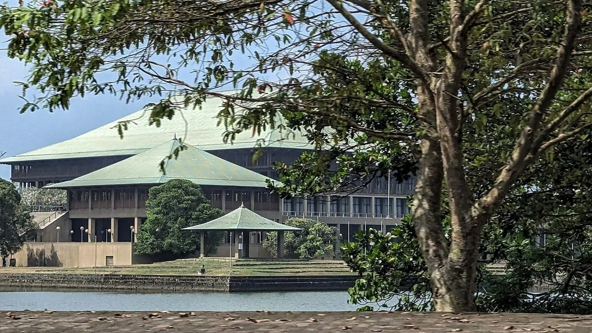 Gmach parlamentu Sri Lanki z zielonymi dachami na wyspie na jeziorze Diyawanna w Kotte, widziany zza drzew