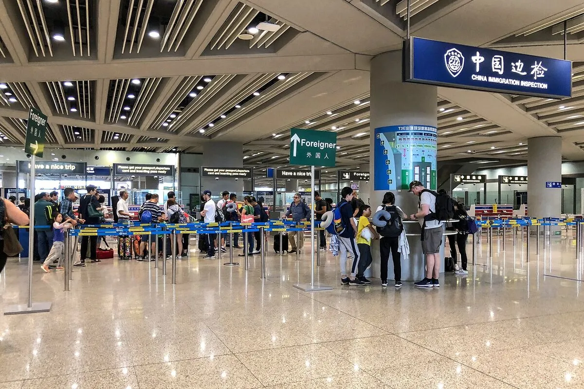 Podróżni w kolejce do kontroli granicznej China Immigration Inspection na lotnisku w Pekinie, obok drogowskaz „Foreigner” dla cudzoziemców