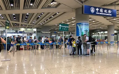 Podróżni w kolejce do kontroli granicznej China Immigration Inspection na lotnisku w Pekinie, obok drogowskaz „Foreigner” dla cudzoziemców