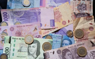 Meksykańskie banknoty i monety peso rozłożone na stole