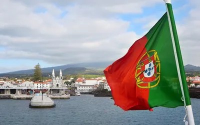 Portugalska flaga na promie wpływającym do portu w Madalenie na wyspie Pico