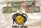 Banknoty 50 i 100 dolarów jamajskich oraz trzy monety na koszulce z napisem Smile Mon