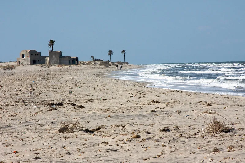 Piaszczysta plaża Dżerby z palmami i wzburzonym morzem