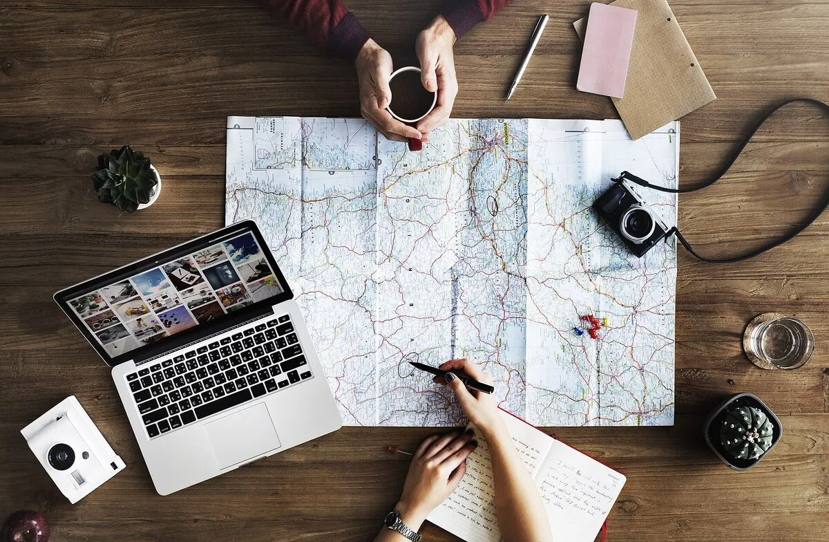 Mapa, laptop i kawa na biurku – planowanie wyjazdu