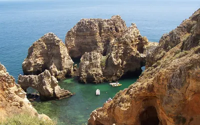 Skalne formacje i turkusowa zatoka z łodziami na wybrzeżu Algarve