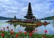 Wielopoziomowa wieża meru świątyni Pura Ulun Danu Bratan na wysepce na jeziorze Bratan na Bali, na pierwszym planie czerwone kwiaty