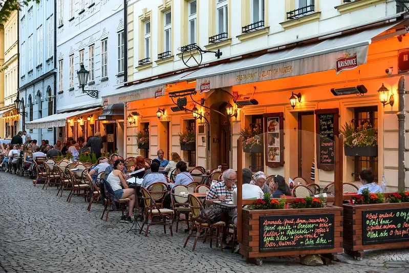 Restauracja z ogródkiem na brukowanej ulicy w centrum Pragi wieczorem