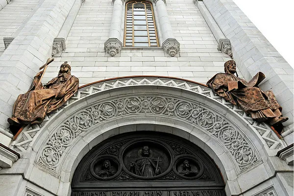 Zdobiony portal z brązowymi rzeźbami po bokach na fasadzie cerkwi