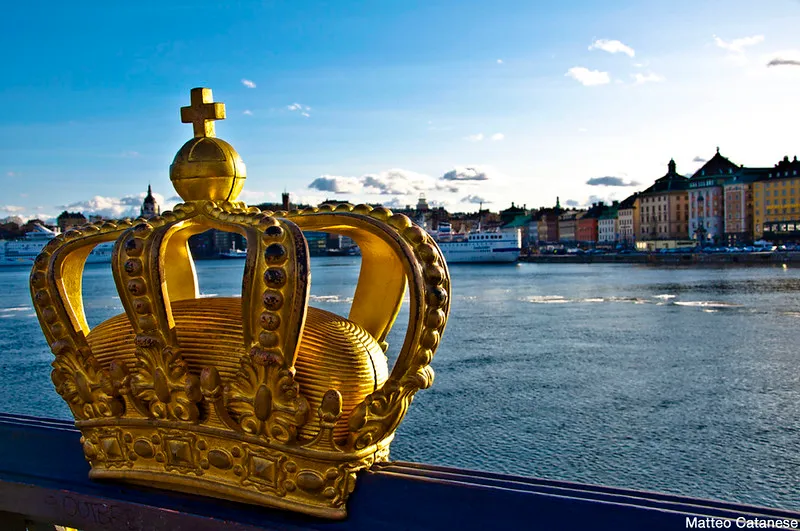 Złota korona na balustradzie mostu Skeppsholmsbron na tle nabrzeża starego miasta w Sztokholmie