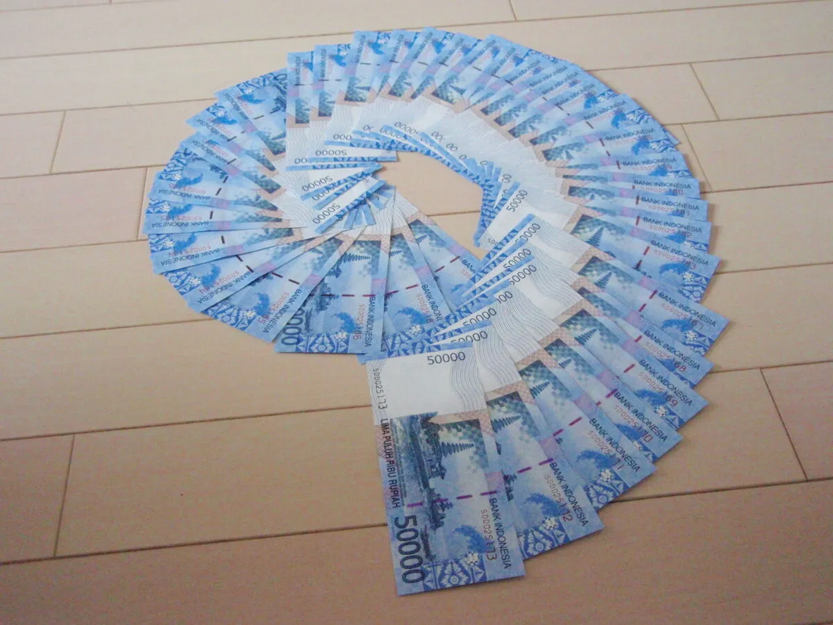 Banknoty 50 000 rupii z serii 2011 ułożone w wachlarz na drewnianej podłodze