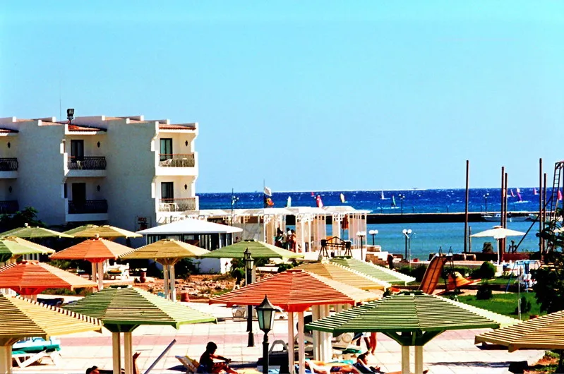 Hotel z kolorowymi parasolami nad Morzem Czerwonym w Safadży, w tle windsurferzy