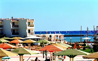 Hotel z kolorowymi parasolami nad Morzem Czerwonym w Safadży, w tle windsurferzy