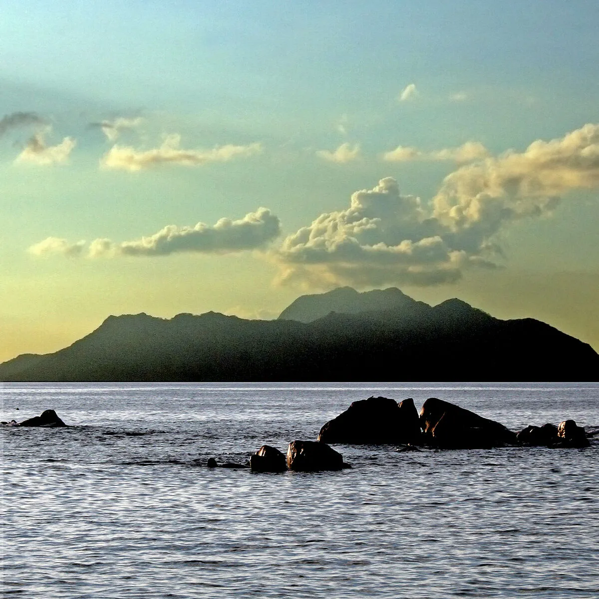 Górzysta sylweta wyspy Silhouette nad oceanem o zachodzie słońca, widziana z Mahé