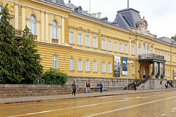 Żółty gmach dawnego pałacu królewskiego przy ulicy wyłożonej żółtą kostką w Sofii