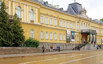 Żółty gmach dawnego pałacu królewskiego przy ulicy wyłożonej żółtą kostką w Sofii