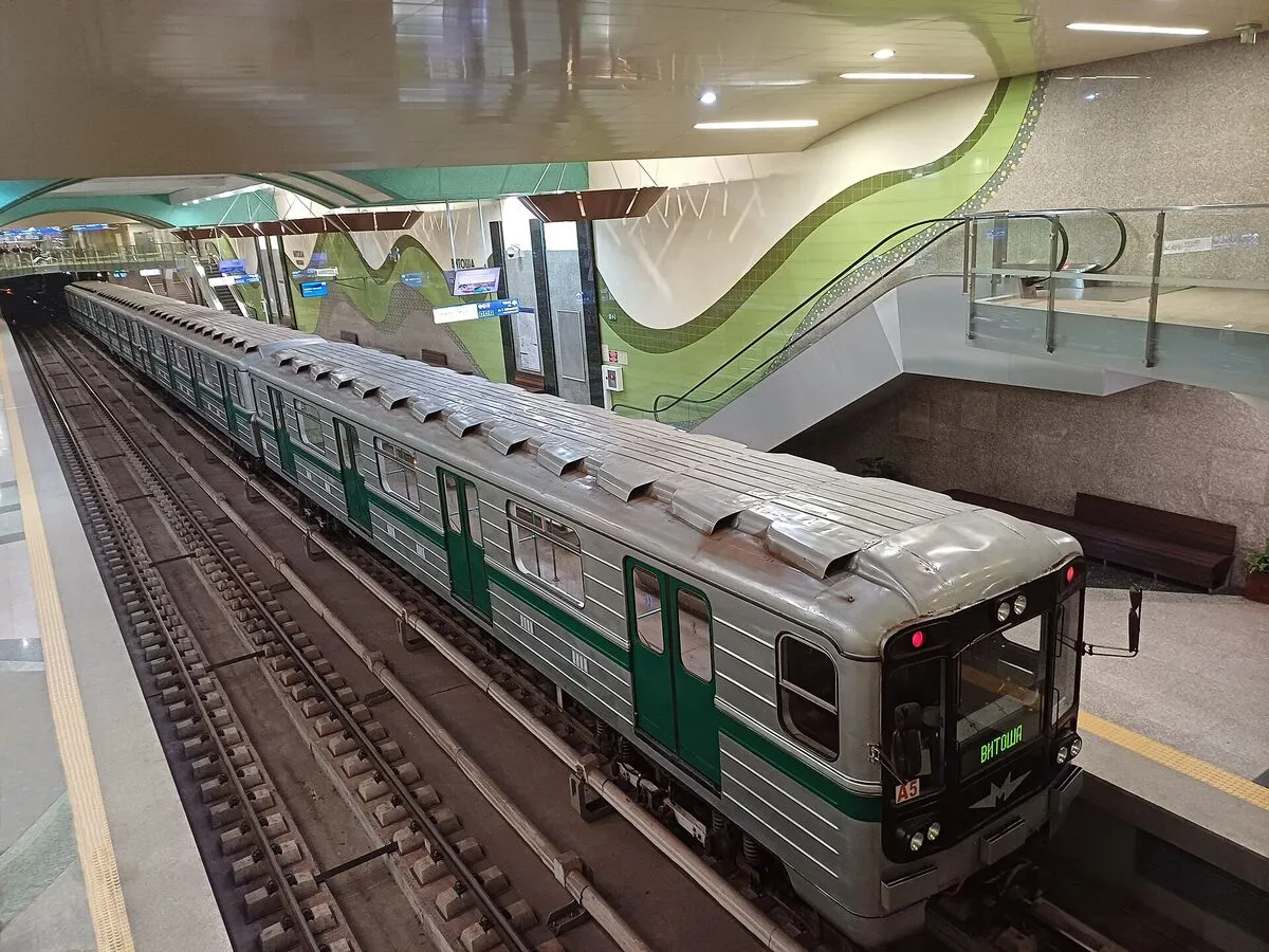 Srebrno-zielony pociąg metra przy peronie stacji Witosza w Sofii, ze ścianami w zielone fale
