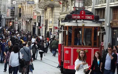 Tłum przechodniów na deptaku İstiklal w Stambule, obok czerwony zabytkowy tramwaj Taksim-Tünel