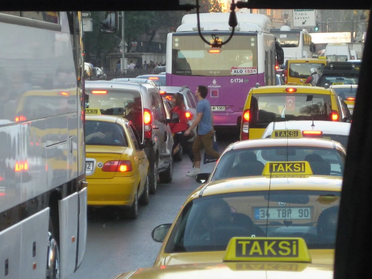 Zakorkowana ulica w Stambule: żółte taksówki, autobus i pieszy przechodzący między samochodami