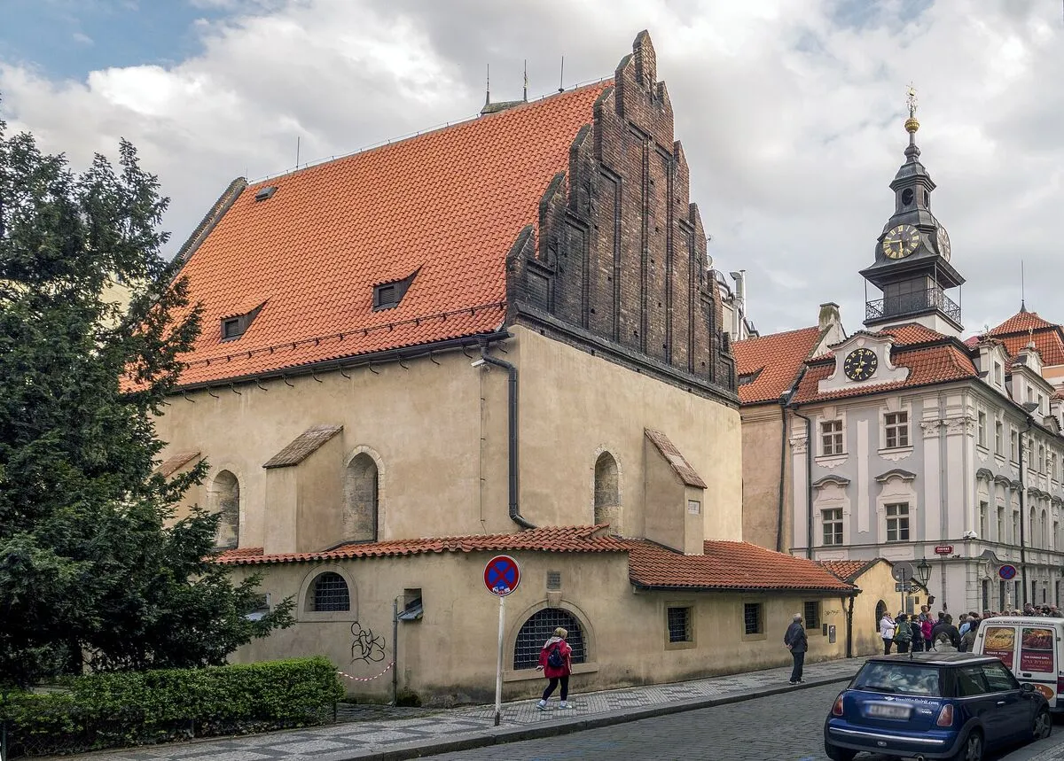 Gotycka Staronowa Synagoga w Pradze ze stromym czerwonym dachem i ceglanym schodkowym szczytem, obok żydowski ratusz z wieżą zegarową