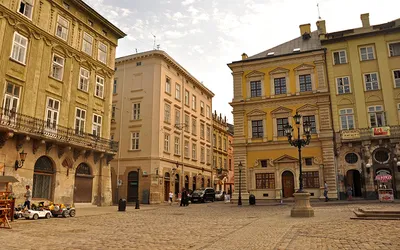 Beżowe i żółte kamienice na narożniku brukowanego Rynku we Lwowie