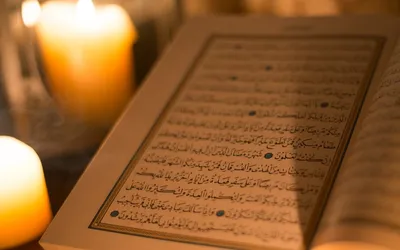 Otwarty Koran z arabskim tekstem w świetle świec