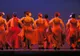 Tancerki flamenco w czerwonych sukniach na scenie, widziane od tyłu