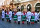 Pary tancerzy w ukraińskich strojach ludowych – białe koszule, zielone spódnice i czerwone buty – tańczą na ulicy w Czerniowcach