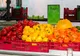 Czerwona, żółta i pomarańczowa papryka w skrzynkach na straganie, obok tabliczka z ceną 3,50 € za kilogram