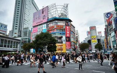Tłum przechodniów na skrzyżowaniu Shibuya w Tokio, otoczonym wieżowcami z reklamami