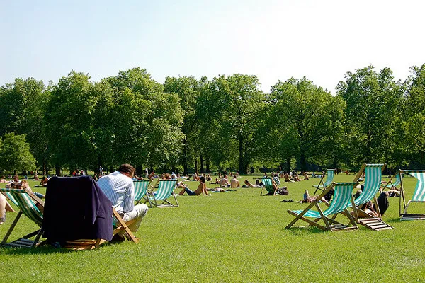 Ludzie odpoczywający w leżakach na trawie w Green Park