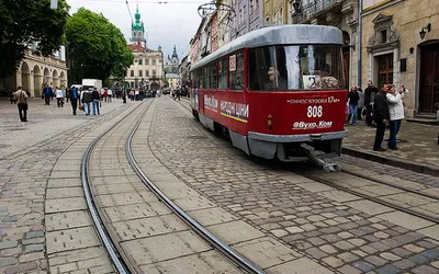 Czerwony tramwaj Tatra na brukowanej ulicy lwowskiego Starego Miasta
