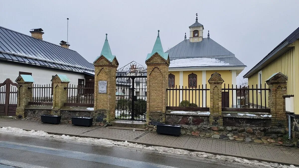 Żółta karaimska kienesa za ceglanym ogrodzeniem w Trokach