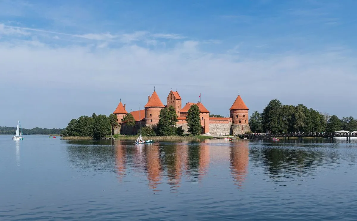 Ceglany zamek w Trokach odbijający się w wodach jeziora Galwe