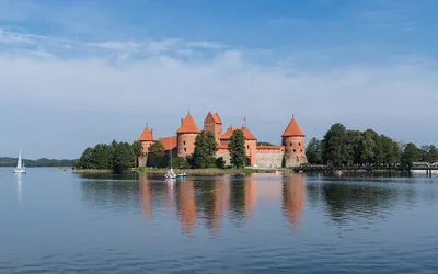 Ceglany zamek w Trokach odbijający się w wodach jeziora Galwe