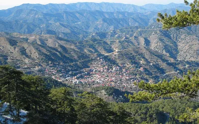 Widok z sosnowego lasu na wioskę Pedoulas w dolinie i pasma gór Troodos
