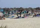Turyści wypoczywający na leżakach pod słomianymi parasolami na plaży w Tunezji