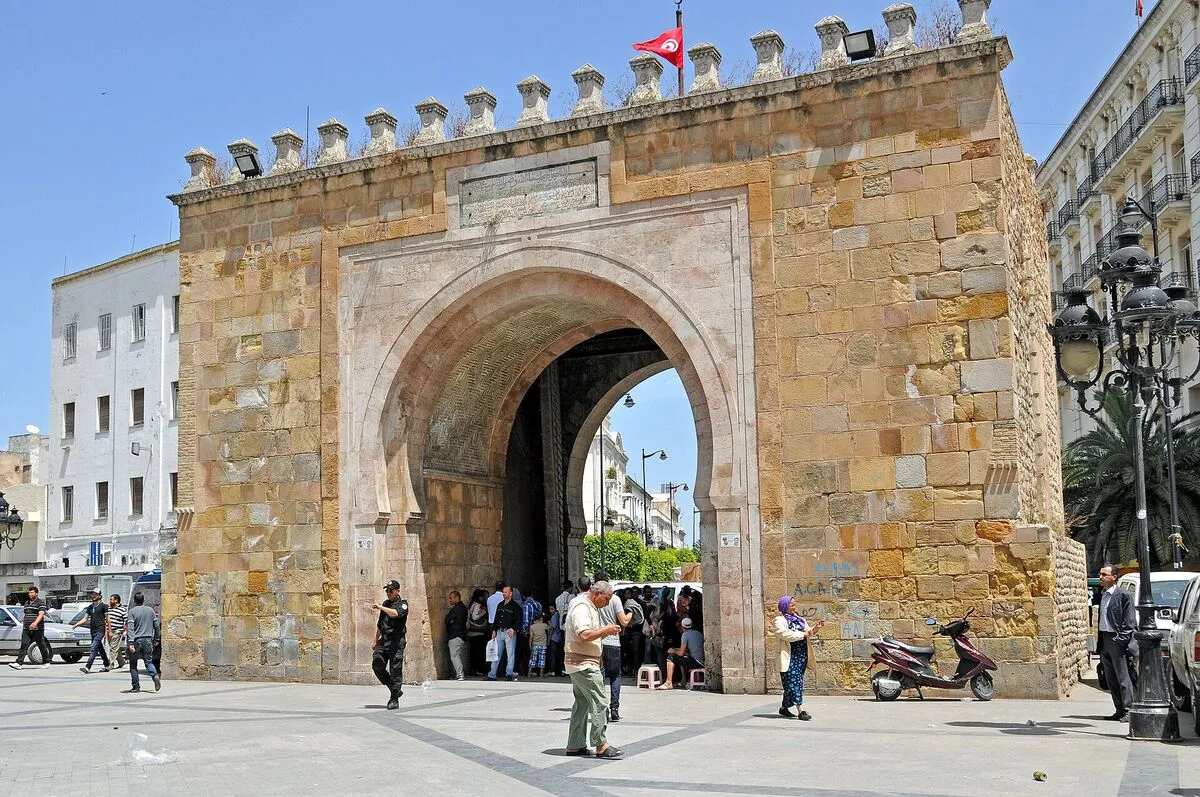 Kamienna brama Bab el Bhar w Tunisie w słoneczny dzień, przed nią przechodnie