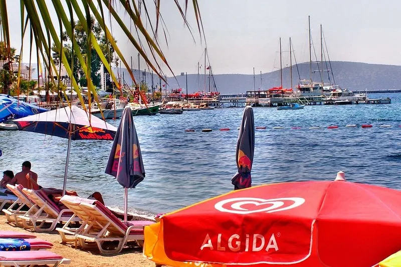Plaża z leżakami i parasolami nad zatoką z jachtami w Bodrum
