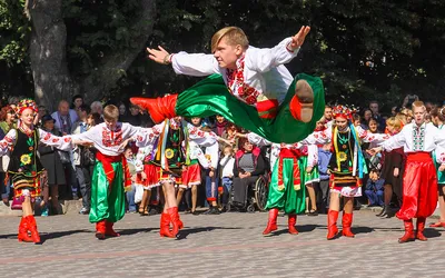 Tancerz w ukraińskim stroju ludowym w wyskoku podczas plenerowego występu zespołu folklorystycznego