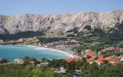 Zatoka w Bašce z długą żwirową plażą Vela, czerwonymi dachami miasteczka i skalistymi górami w tle