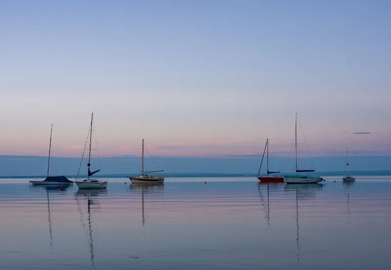 Żaglówki na spokojnej wodzie Balatonu o zmierzchu